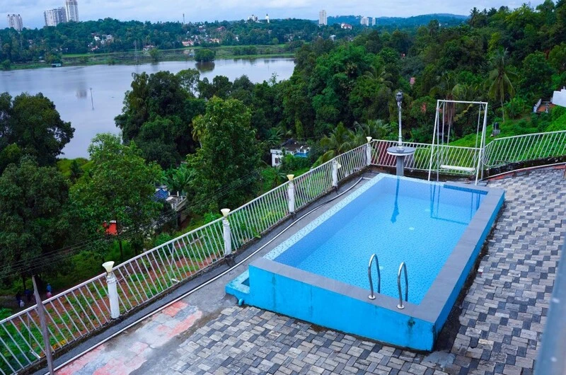 Swimming pool with serene backwater view at Lakshmipuram Palace Kumarakom